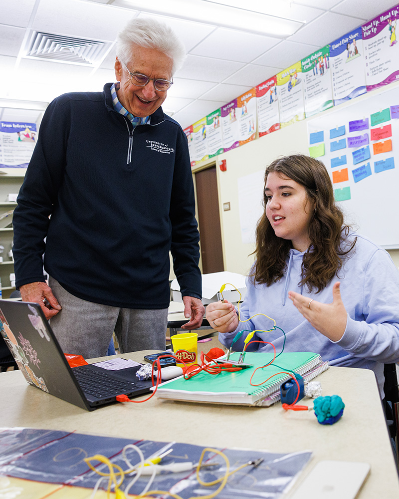 man and woman looking at a laptop while using electrical wires and Play-Doh
