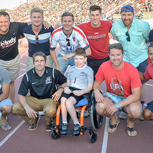 Alumni, students, and family posing for a photo on the track
