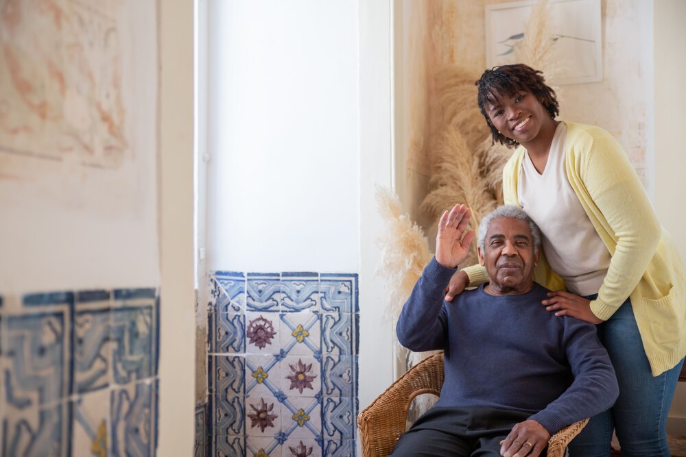 a caretaker with a smiling man in a wheelchair