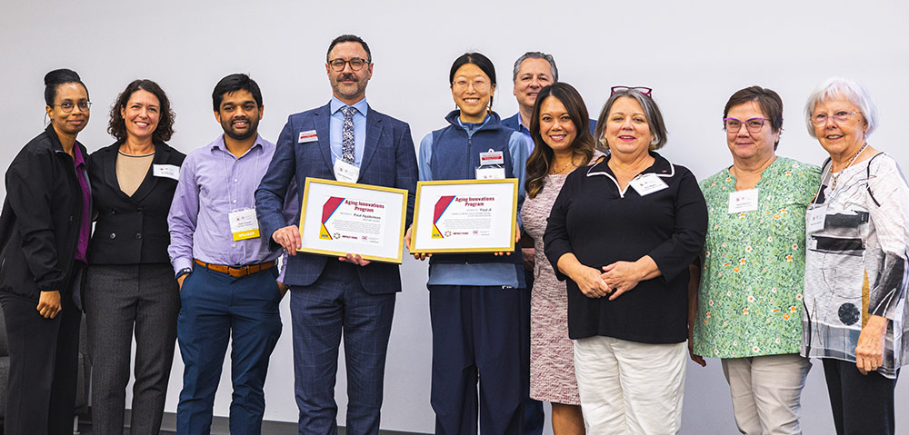 large group on stage with two people holding certificates