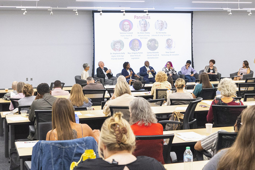 large room with symposium panelists and attendees