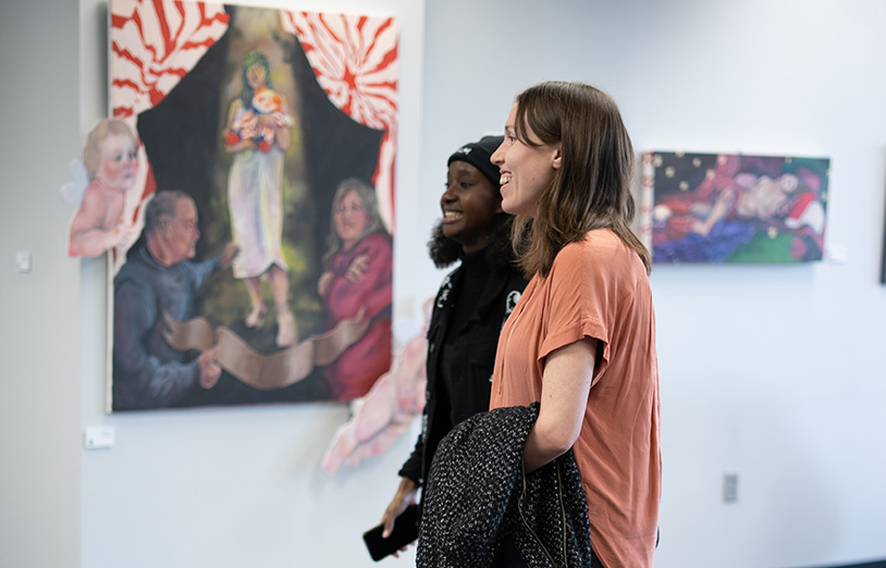 two people enjoy looking at artwork on the wall