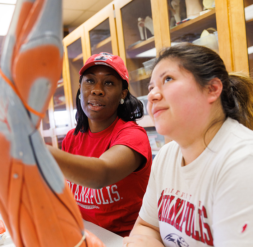 two female students in class looking at an anatomy model