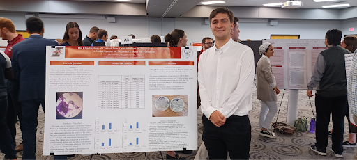 student standing next to his poster presentation