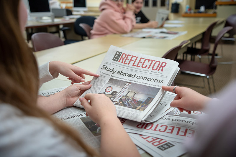 hands holding The Reflector student newspaper