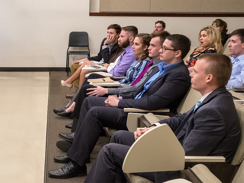 students dressed in formal attire attentively listening