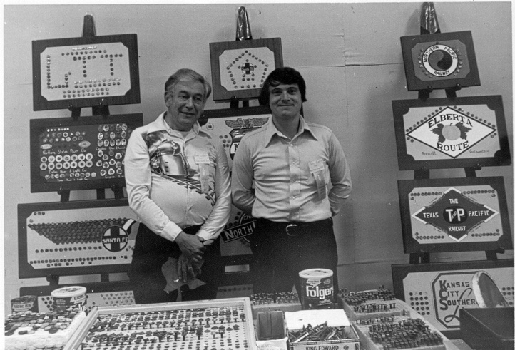 black and white photograph of two men standing with date nails on display