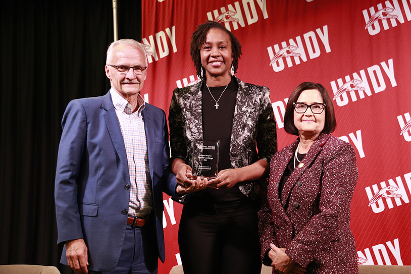 Tamika Catchings holding an award and standing with Kevin Armstrong and President Singh