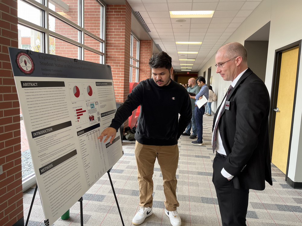 student showing faculty member something on research poster