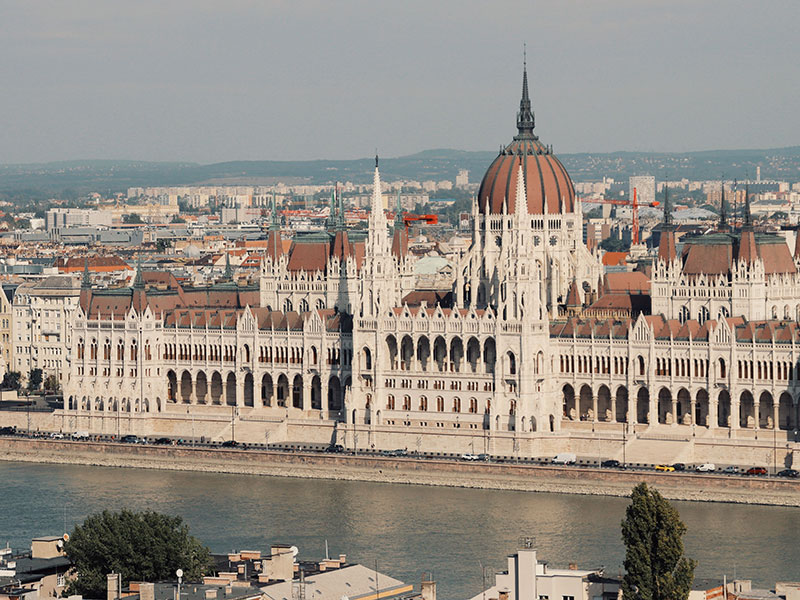 View of the Hungarian Parliament Building with its large dome and spires along the Danube River in Budapest.