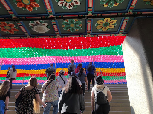 UIndy students going up a flight of stairs in South Korea. At the top, there are lots of rows of brightly colored paper lanterns.