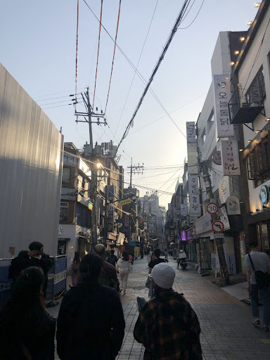 UIndy students walking down a street lined with shop signs and power lines in South Korea.