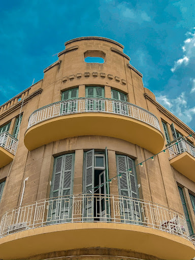A tan brick house with round balconies in Cyprus. The blue sky is in the background.