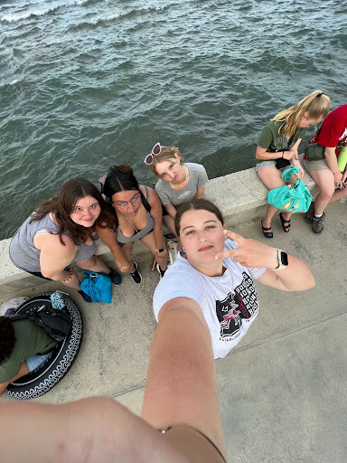 A selfie of Rosalea and other students sitting on a bridge near the ocean.