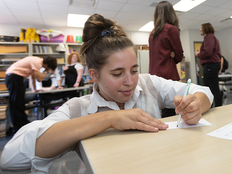 woman in a classroom writing on paper