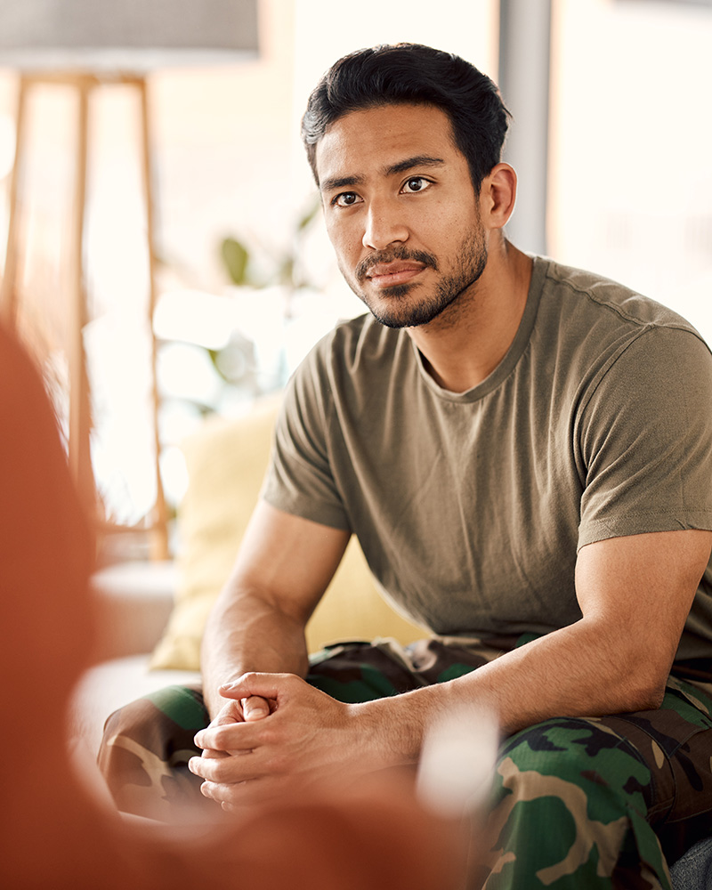a man wearing Army fatigues is listening to a person talking