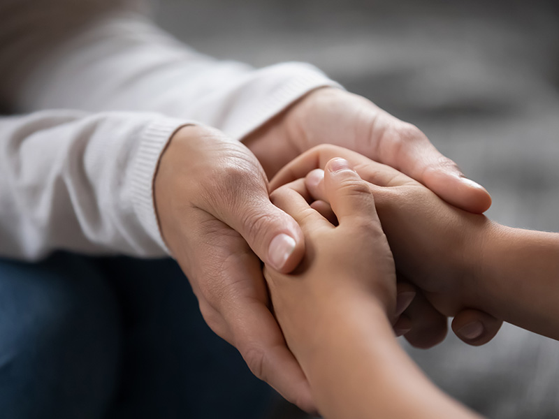 a pair of adult hands holding a child's hands