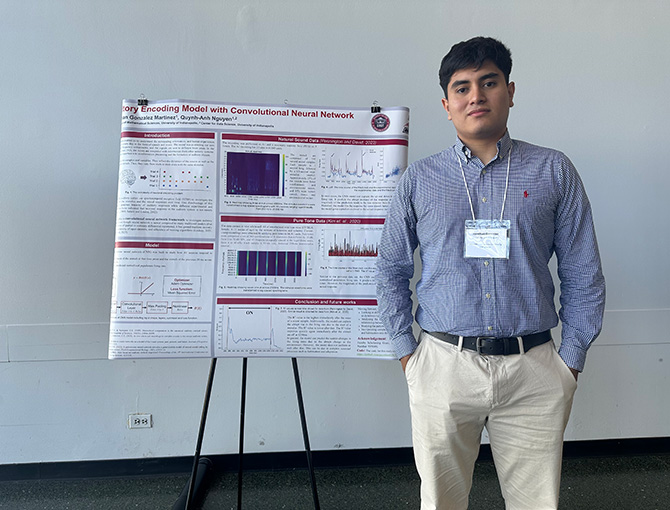 young man standing next to his poster presentation