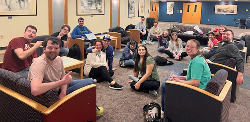 students and staff sitting together in a lounge area