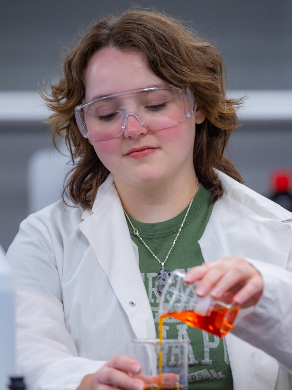 Grace Rout pours liquid from one beaker to another