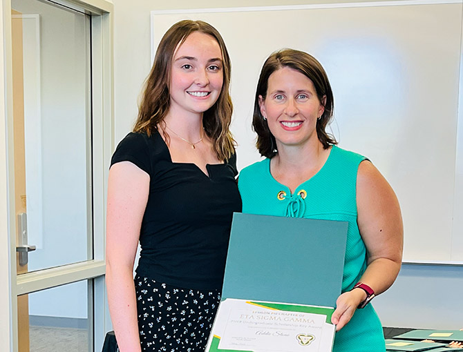 female student with professor holding an award