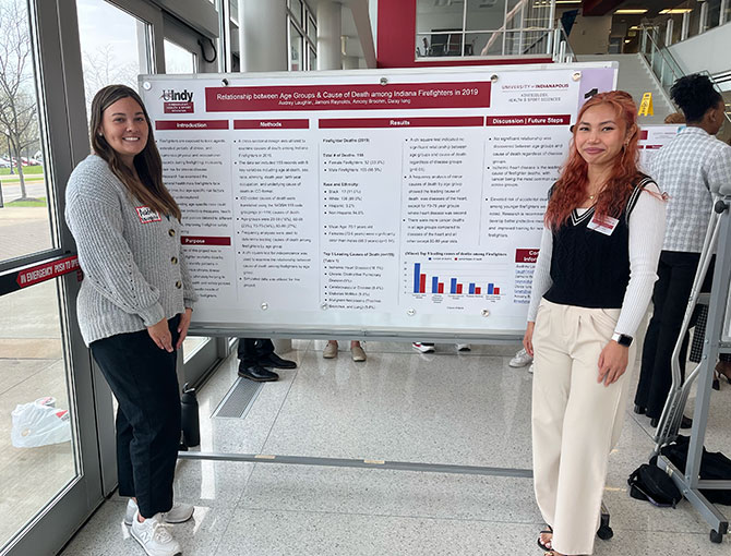 two female students standing next to their poster presentation