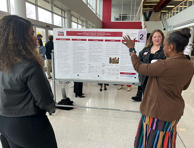 student presenting her poster in front of visitors