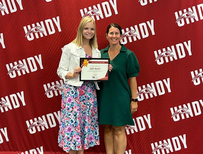 female student receives an award, standing next to professor