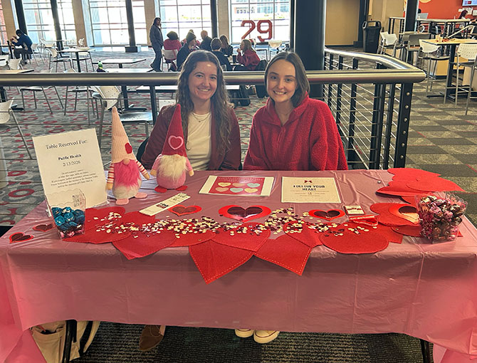 two female students sitting at a public health table