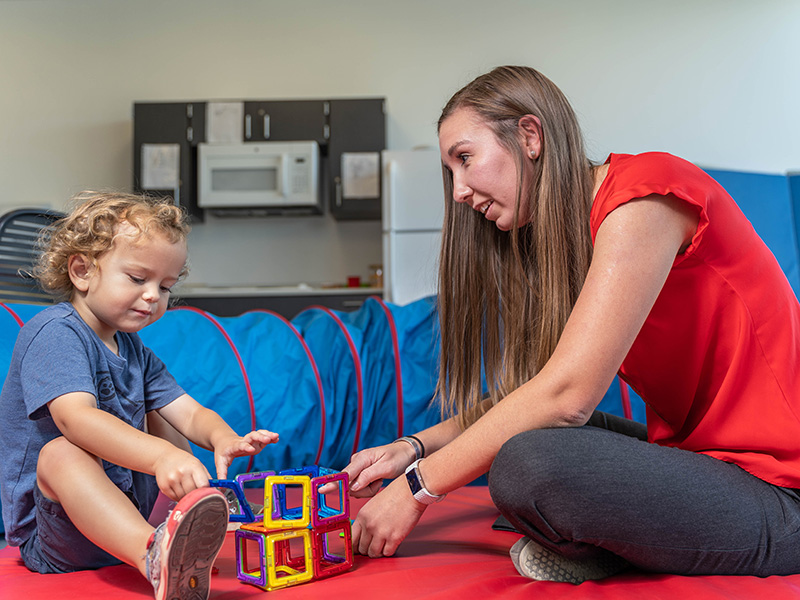 student and young child playing with blocks