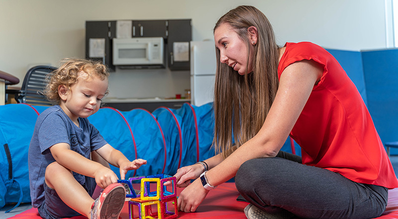 student and child playing with blocks