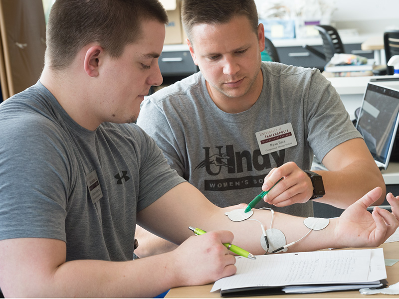 two students in class, and one has electrode pads on his arm