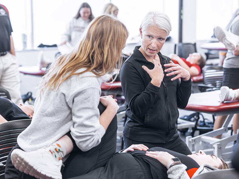 Physical Therapy student interacting with a patient while a professor offers assistance