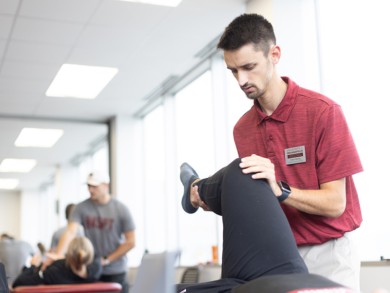 Physical Therapy students practice stretching patients in a medial table in a classroom setting. 