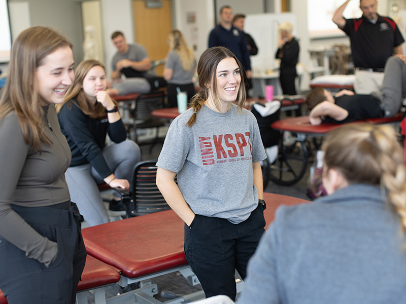 students smile as they converse amongst physical therapy tables
