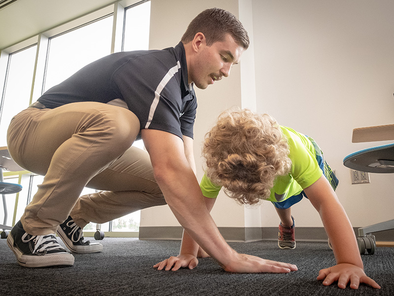 Physical Therapy student interacts with a young child as they do an exercise