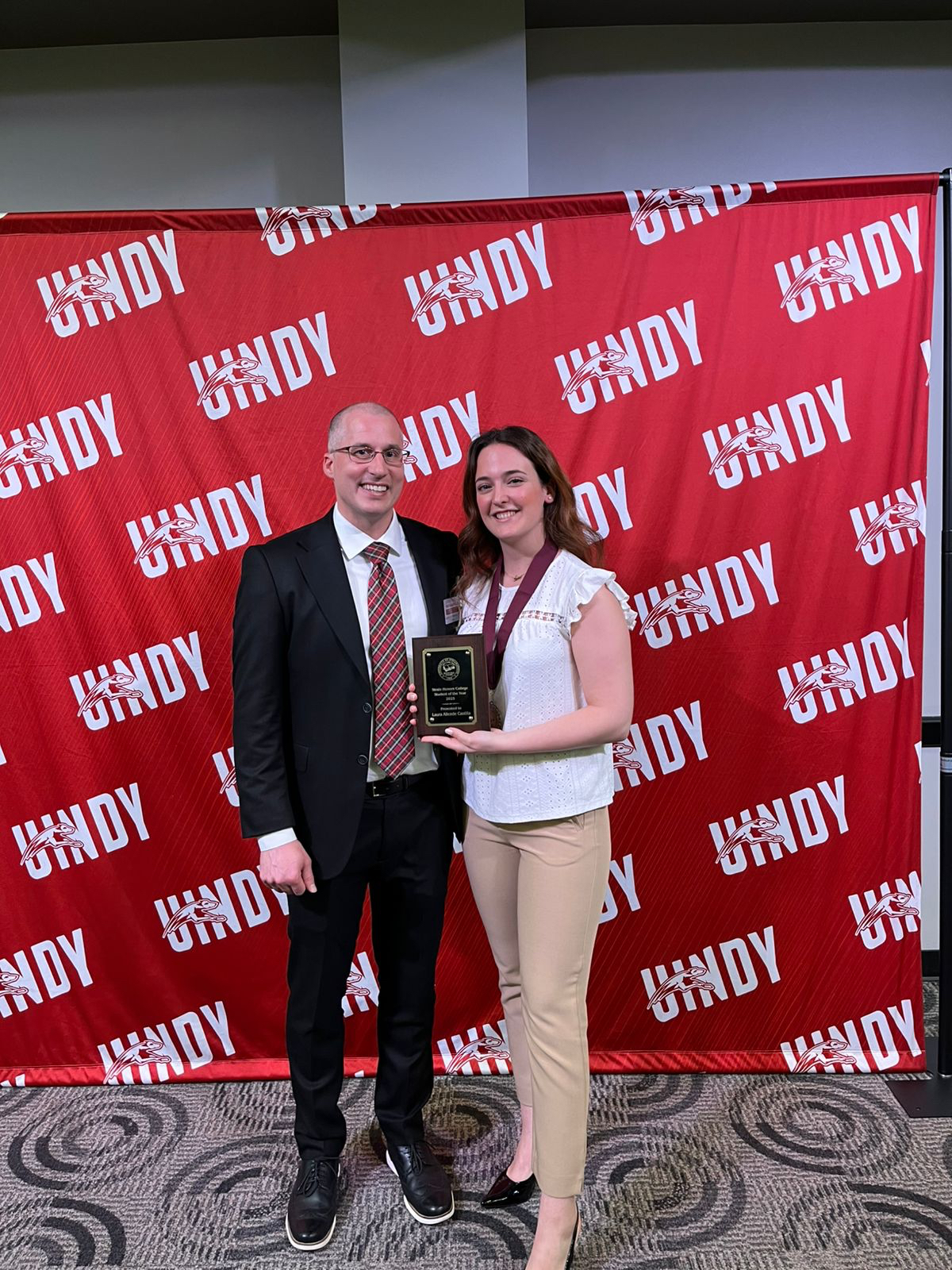 student holding award standing next to a faculty member