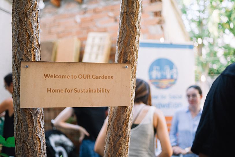 A sign on a tree that says: Welcome to OUR Gardens. Home for Sustainability.