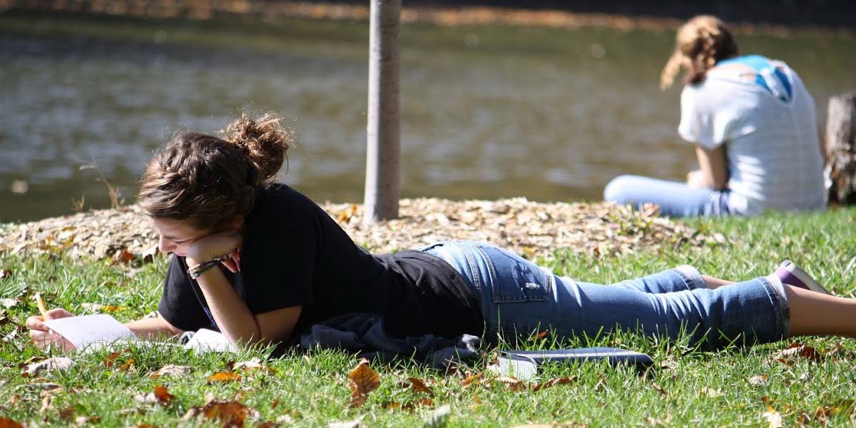 lady laying on grass, reading