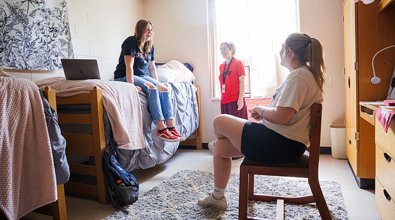 three female roommates laughing together in their residence hall