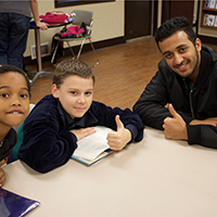 A man with two children giving a thumbs up